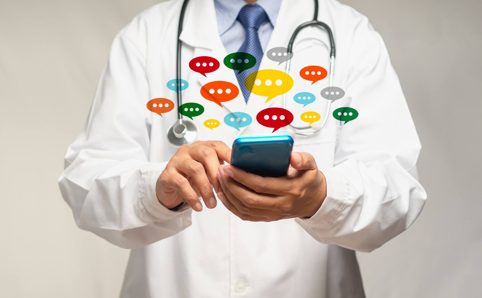 Doctor using a smartphone with colorful chat icons on application digital web and social media while standing in the hospital